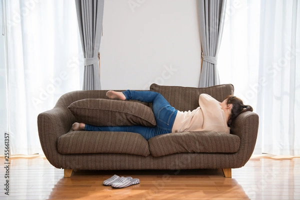 Fototapeta ソファでゴロゴロする女性