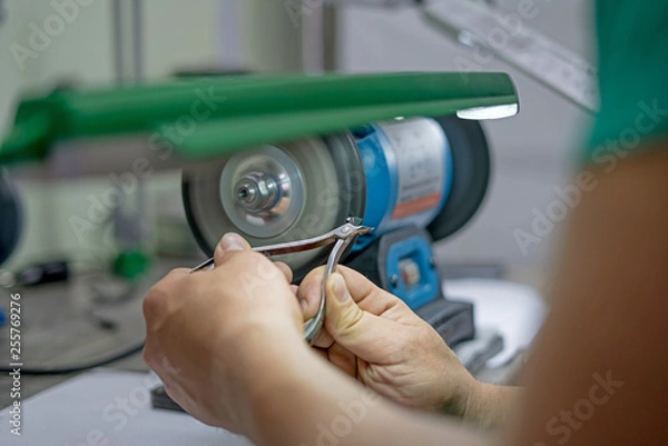 Obraz master man sharpens the machine scissors so they were sharp