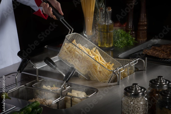 Obraz Chef is cooking french fries on a kitchen counter