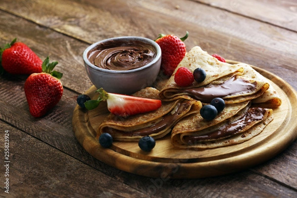 Fototapeta Delicious Tasty Homemade crepes with chocolate or pancakes with raspberries and blueberries on rustic wood
