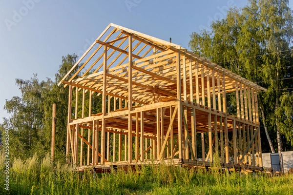 Fototapeta wooden interior frame of a new house under building, architectural residential construction stick built home framework.
