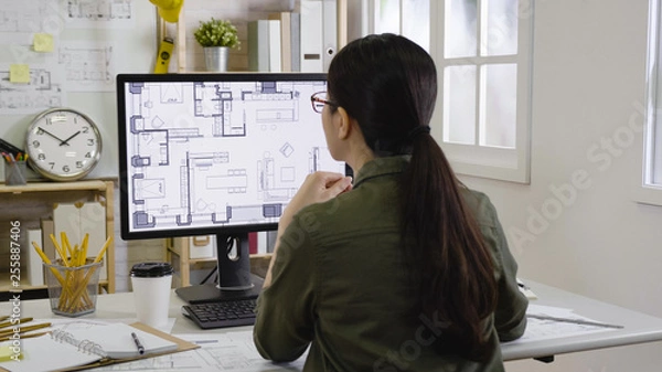 Obraz asian woman interior designer looking floor plan of new house indoor design on monitor concentrated thinking idea. Blueprint architect construction project sketch concept on laptop computer screen.