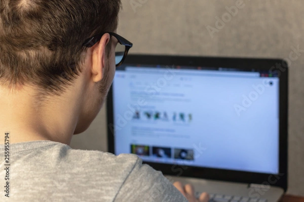 Obraz man with glasses working at a laptop at home. soft focus. home work concept