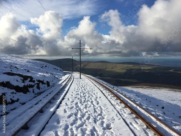 Fototapeta Snow covered rail tracks of the the Snaefell Mountain Railway, an electric mountain railway on the Isle of Man. It joins the village of Laxey with the summit of Snaefell, at 2,036 feet above sea level