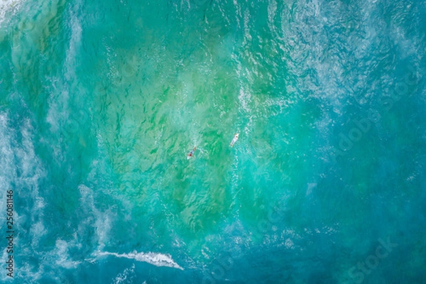 Fototapeta Two surfers rowing in opposite directions - aerial view with copy space