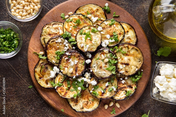 Obraz Fried eggplant with feta, pine nuts, fresh herbs (cilantro, parsley) and olive oil. Tasty vegetable snack, summer, spring food, picnic