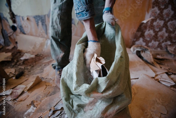 Obraz Worker cleans the trash in the apartment in the bag