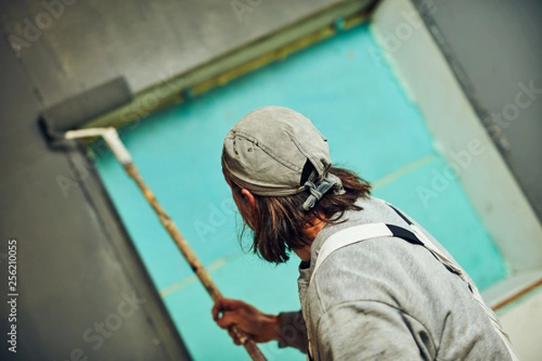 Fototapeta Painter painting walls with a extender roller indoors.