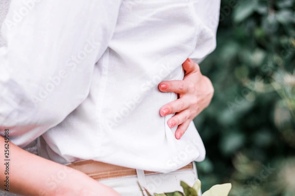 Fototapeta Bride hugs groom by the waist. Horizontal photo