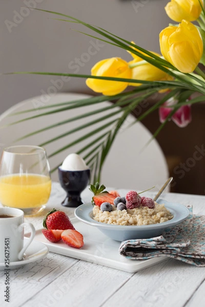 Fototapeta Oatmeal porridge with fresh blueberries, raspberries, muesli and almonds in red bowl on white table. Healthy breakfast, healthy eating, vegan food concept. Colorful breakfast for kids