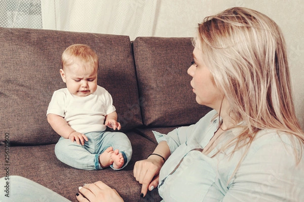 Fototapeta Problems of understanding mother and child. A young woman mom is a nanny and a little disgruntled and angry child. The conflict of a small child with a mother or nanny.