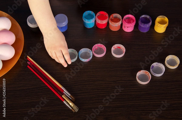 Fototapeta a child paints Easter eggs. hand, paintbrush and paint on the table. preparation for Easter.