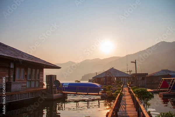 Fototapeta Soft sunlight in the morning with wooden floating bridge, the lake and mountain view for time of freedom on the floating home stay.