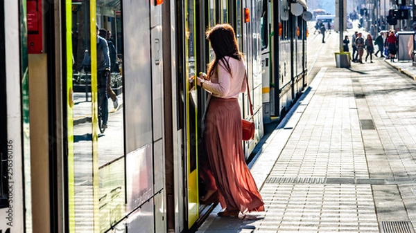 Fototapeta An unidentified female with a long dress is getting onboard a Melbourne Australia city tram in the central business district