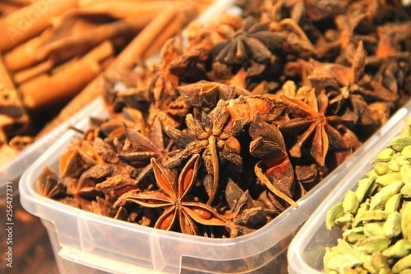 Obraz Fragrant cinnamon in plastic containers on a food court. Spices and spices closeup. Anise flowers with and cinnamon sticks.