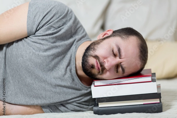 Fototapeta Young man is sleeping on his books. White background