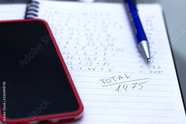 Fototapeta Phone calculator, notebook with calculations written by hand.