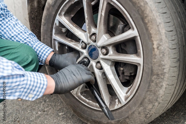 Fototapeta Worker fixing car wheel after change, closeup