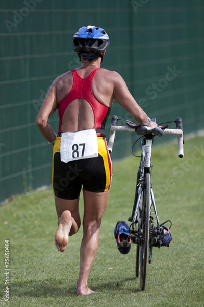 Obraz triathlète poussant son vélo en zone de transition