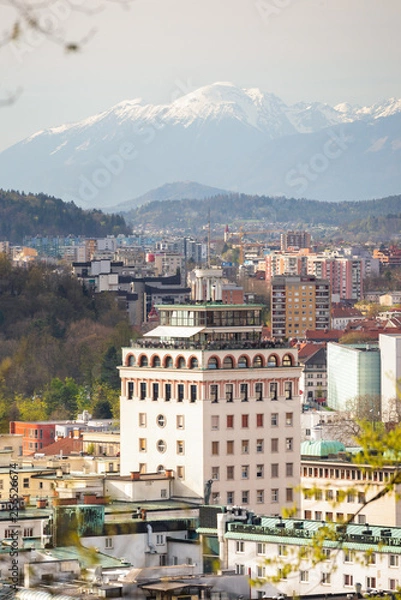 Fototapeta Neboticnik building and Ljubljana old town with mountains as a backdrop in Ljubljana, Slovenia