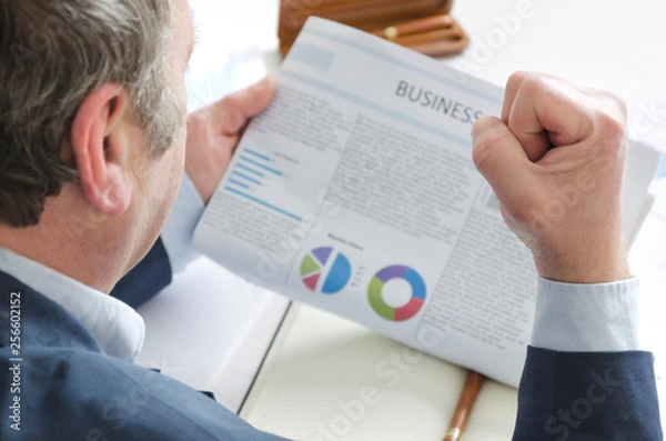 Obraz Businessman reading great news and making winning sign - make a fist. Or businessman making a fist because he is angry about bad business news