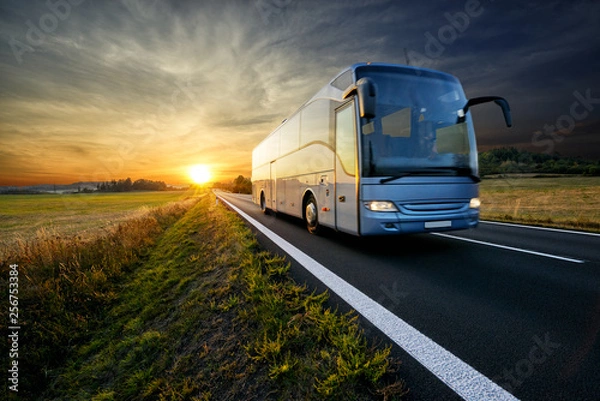 Obraz Bus traveling on the asphalt road in rural landscape at sunset