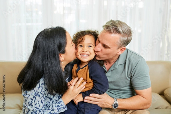 Fototapeta Parents kissing daughter