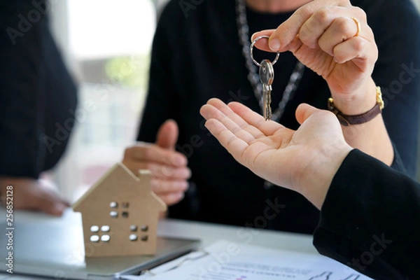 Fototapeta Real estate manager agent giving keys to buyer or investor who's owner of resident or land after credit approved by bank, deposit payment and agreement or contract completely signed at office.........
