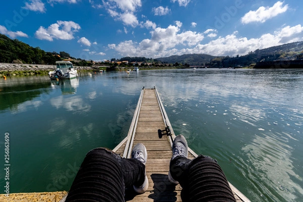 Obraz persona sentada en un puerto con un lago o rió de fondo cielo despejado