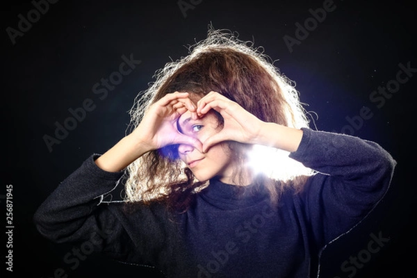 Obraz Emotional portrait of a girl with long curly hair on a black background,