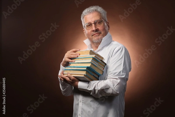 Fototapeta Scientific thinker, philosophy, elderly gray-haired man in a white shirt with a books, with studio light