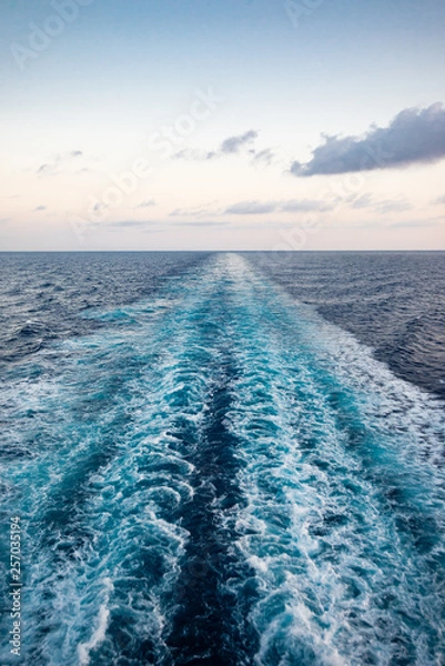 Obraz Scenic view of the sea from the stern of a luxurious cruise ship, against the sunrise on a beautiful blue sky