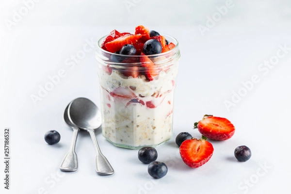 Fototapeta Overnight oats with chia seeds and fresh strawberries and blueberries in a glass jar. Healthy breakfast.