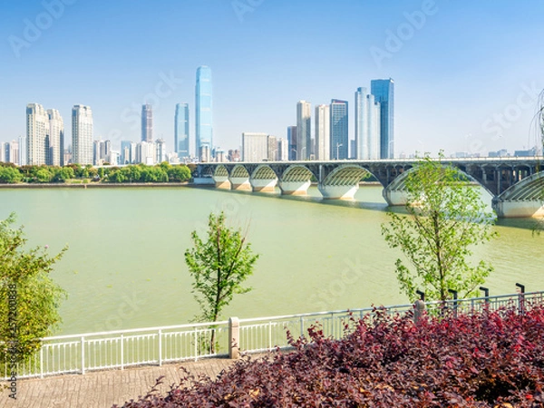 Obraz Bridge across Xiang river in Changsha, capital of Hunan province of China, leading to Orange Isle, with tall downtown buildings in the background.
