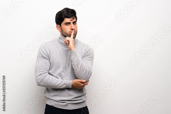 Obraz Young man over isolated white wall showing a sign of silence gesture putting finger in mouth