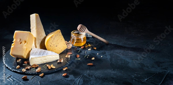 Fototapeta Different kinds of cheese with nuts and honey on dark background, copy space