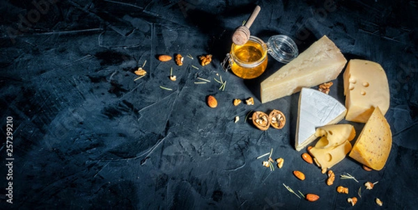 Fototapeta Different kinds of cheese with nuts and honey on dark background, copy space
