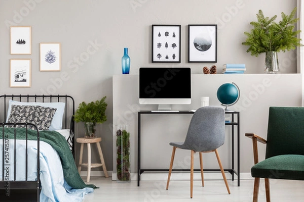 Fototapeta Branches of spruce in glass vases in classy bedroom and workspace for teenager, real photo with posters on empty grey wall