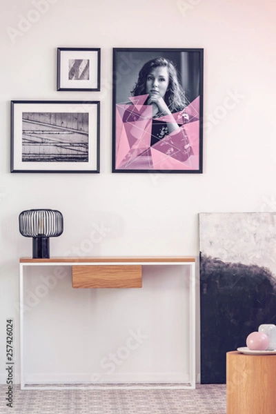 Fototapeta Posters in black frames on white wall in spacious hall with console table with lamp