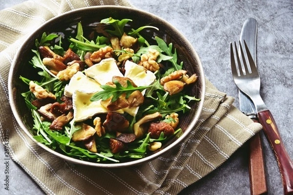 Fototapeta Mushrooms, dried figs and walnut salad with brie cheese. Top view salad isolated