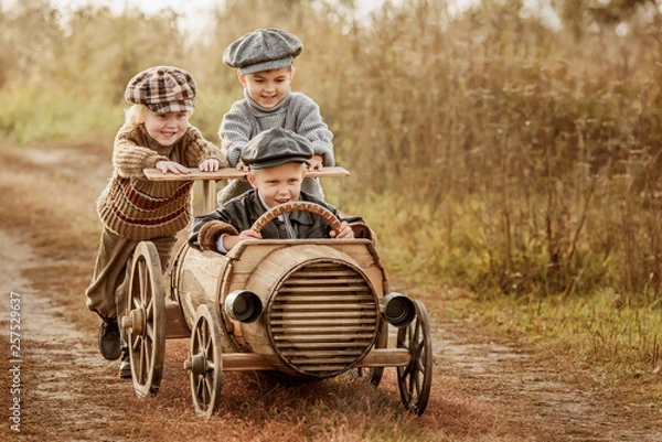 Fototapeta Dzieci jeżdżą na prowizorycznym drewnianym samochodzie wyścigowym