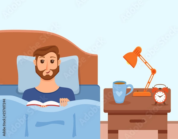 Fototapeta Guy lying on bed in home bedroom and reading a book in her hands