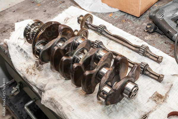 Obraz Close-up of a car crankshaft removed for replacement on a workbench in a vehicle repair shop. Auto service industry.