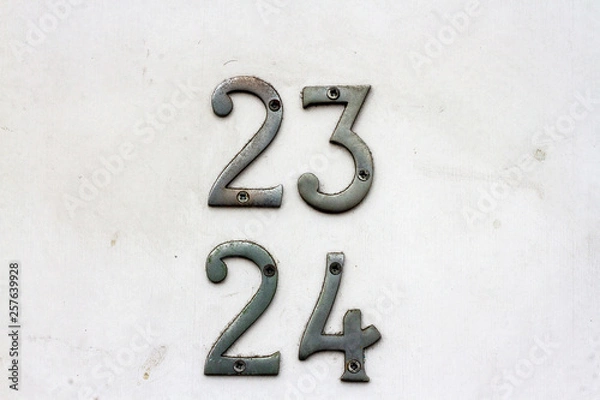 Fototapeta House number 23 and 24 with the twenty-three and twenty-four in silver on a white but dirty door