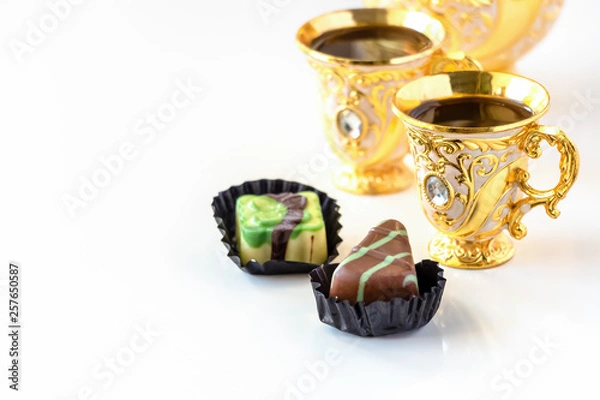 Obraz Still life with traditional golden arabic coffee set with dallah, cup and chocolate candy. White background.