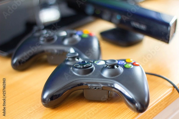 Fototapeta Close up black gaming controllers on wooden table, gamepad for video game at home