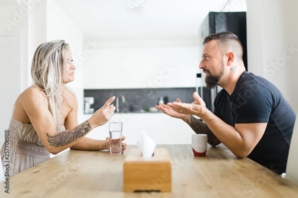 Fototapeta Man and woman sitting by table on opposite side and arguing problems