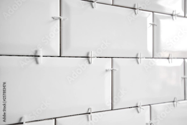 Obraz Ceramic tile lying. Installing new subway or metro tiles in bathroom, shower or kitchen back splash during home renovation. Placing or taking out tile spacers with hands and pliers.
