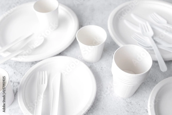 Obraz set of empty reusable disposable eco-friendly plates, cups, utensils on light white and grey concrete table top with copy space. Top view. 
