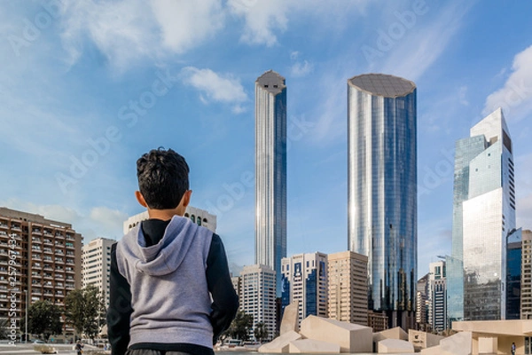 Fototapeta Young kid looking at Abu Dhabi city - Architecture and famous skyscrapers of Abu Dhabi skyline with beautiful clouds, World Trade Center, UAE